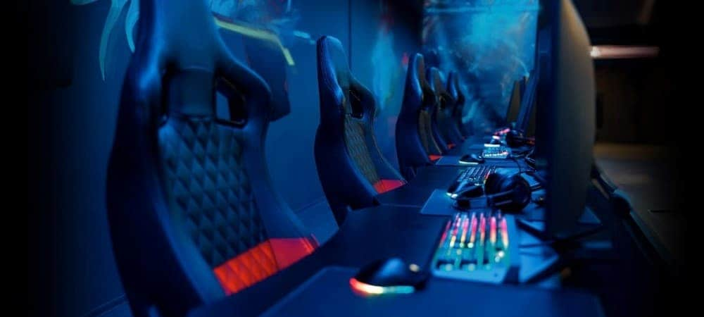 A row of eSports performance gaming setups with headsets, keyboards, monitors, mice, and chairs.